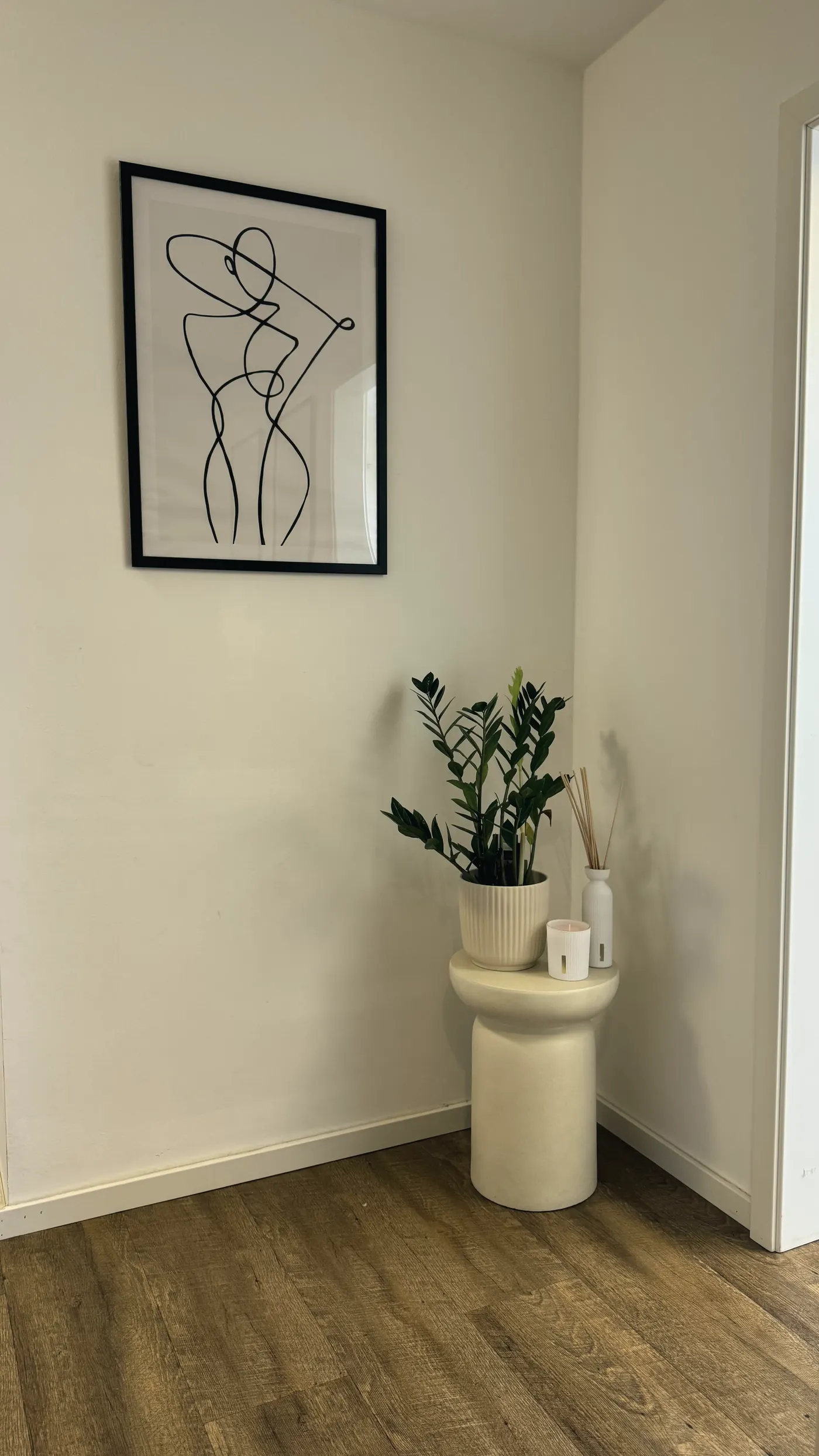 Zimmerpflanze auf einem hellen Sockel unter einem Line-Art-Bild
