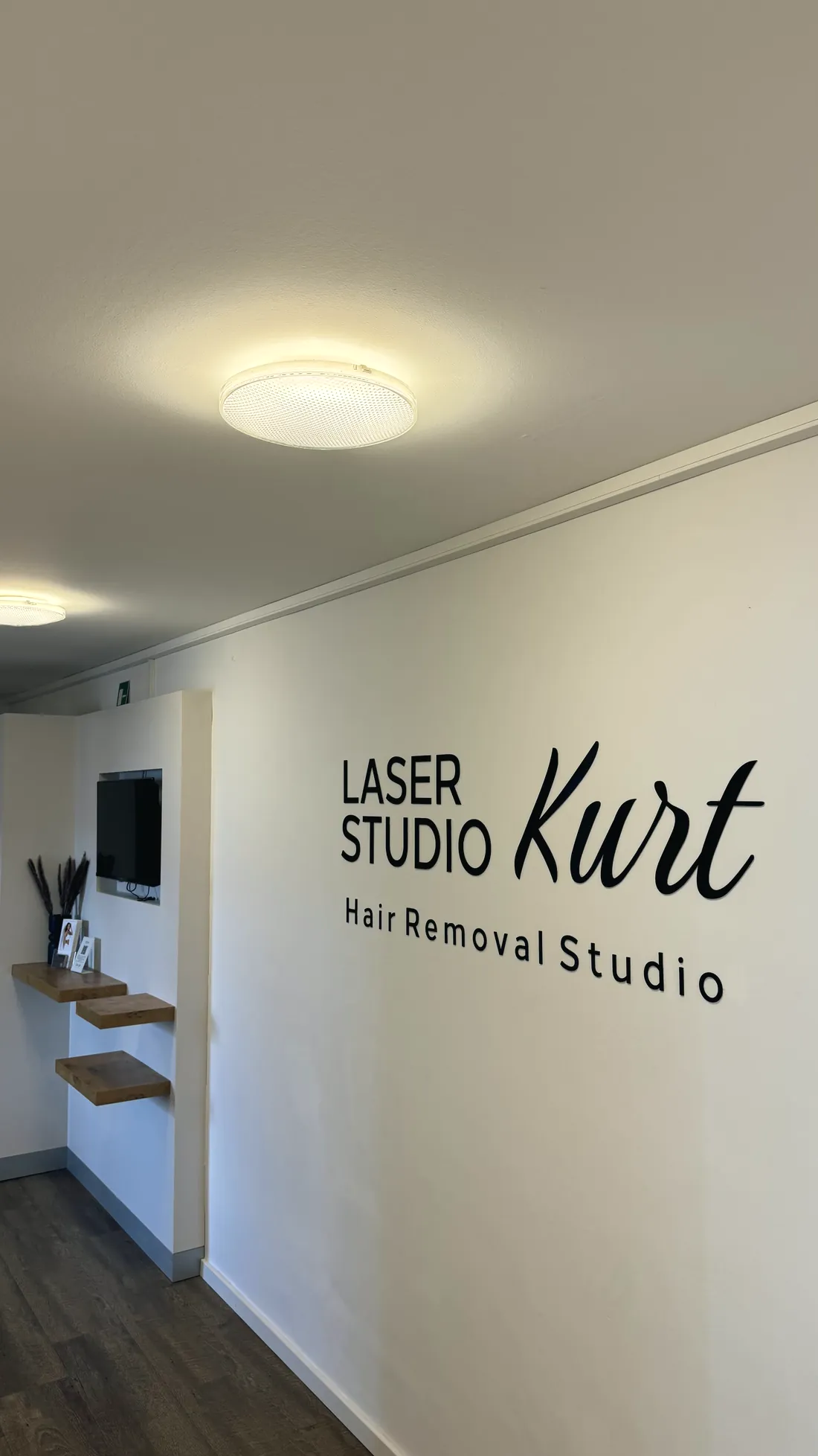 Der Schriftzug Laser Studio Kurt im Eingangsbereich, beleuchtet von der Deckenleuchte